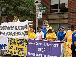 Falun Gong-utövare håller upp banderoller när marschbandet Tian Guo spelar